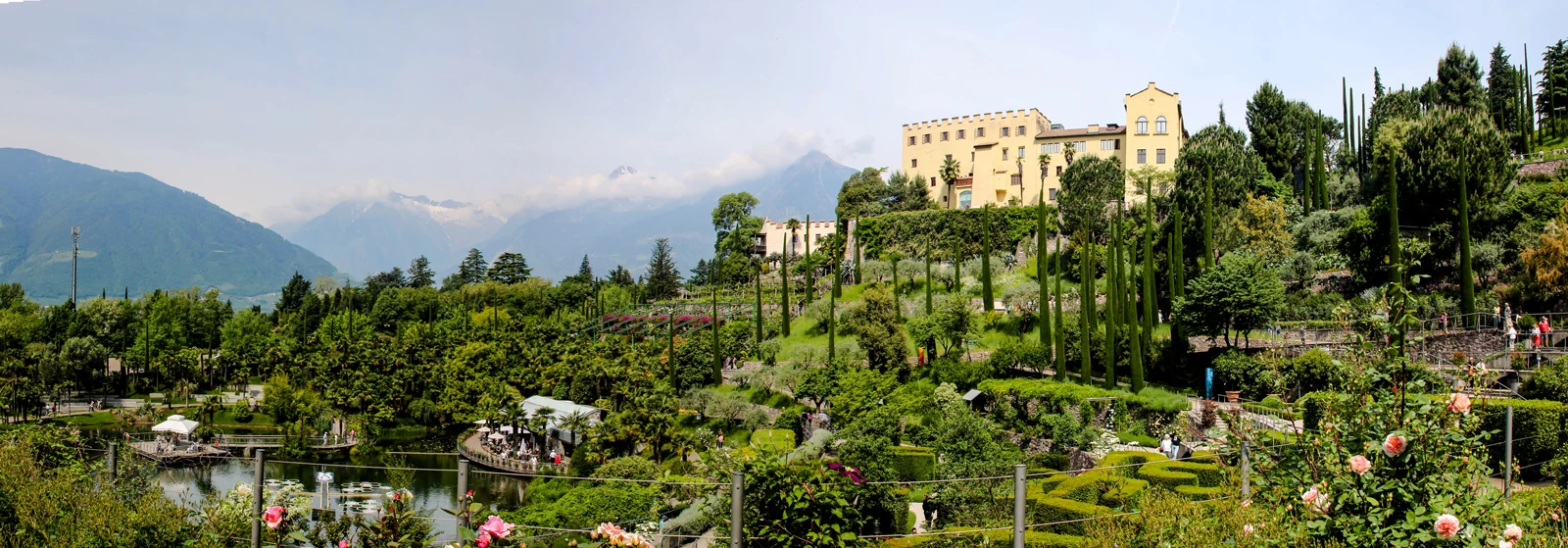 A scenic landscape over Italy's wine country with a large building and sprawling gardens below