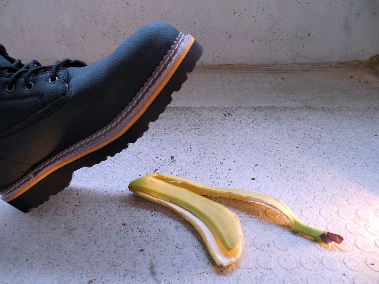 A boot about to step on a banana skin on the floor