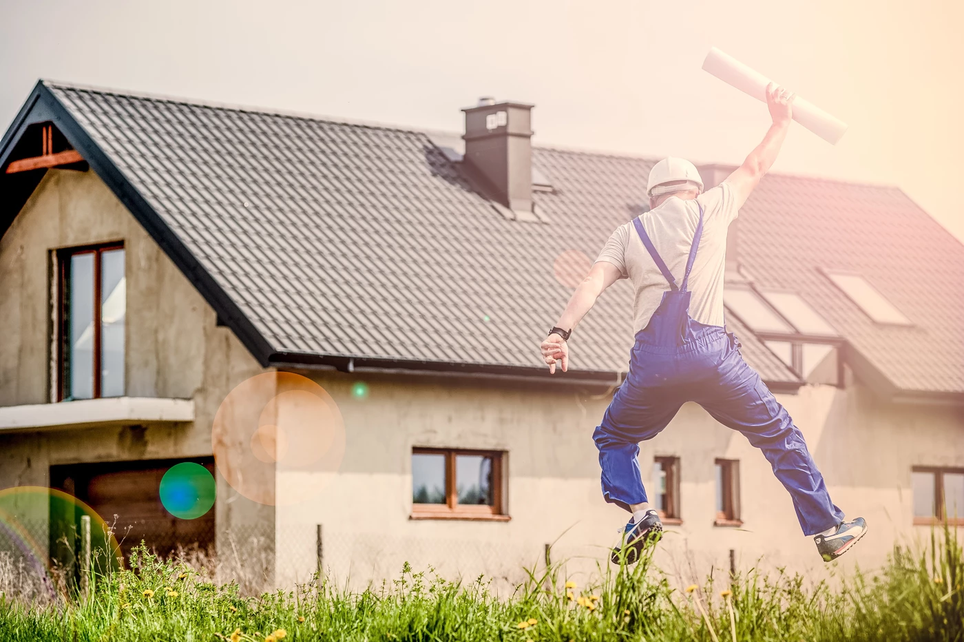 A surveyor jumping in the air holding a rolled up sheet of paper in-front of a property