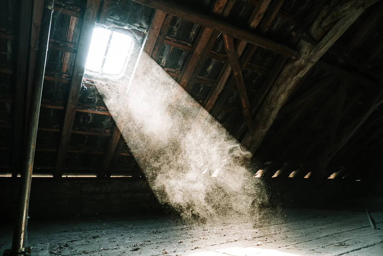 A dusty dilapidated loft space with a sun beam bursting through the window 