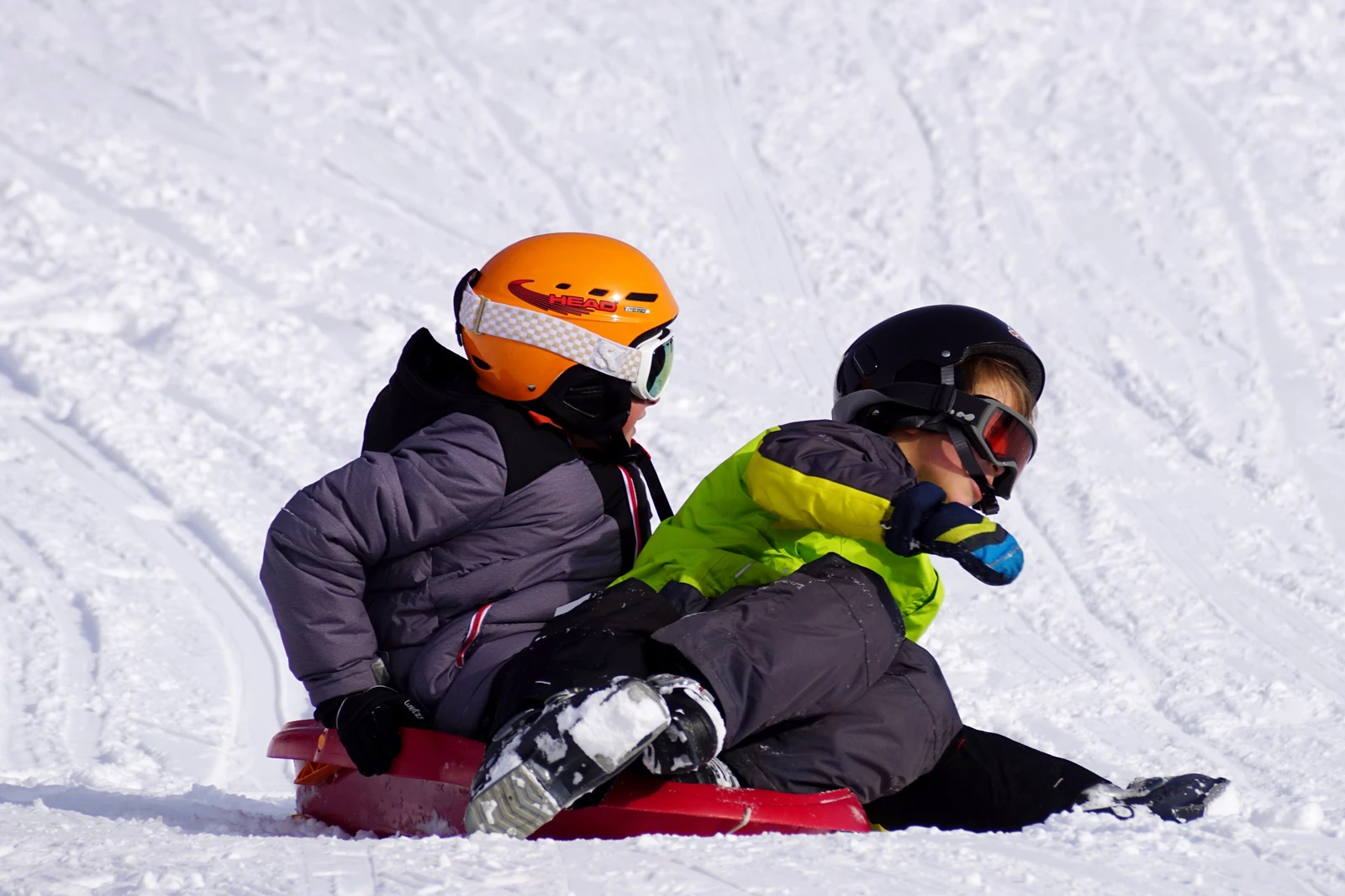 Two children on a sledge going down a snowy slope