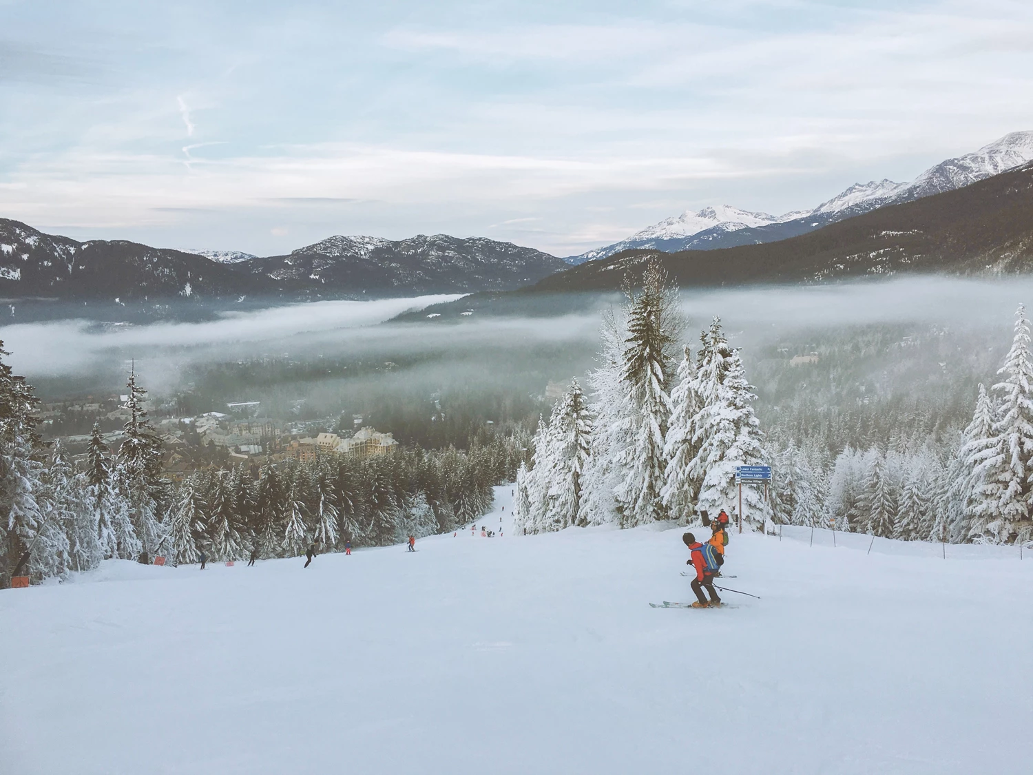 A view down a steep snowy slope on a ski resort with a scenic mountainous view