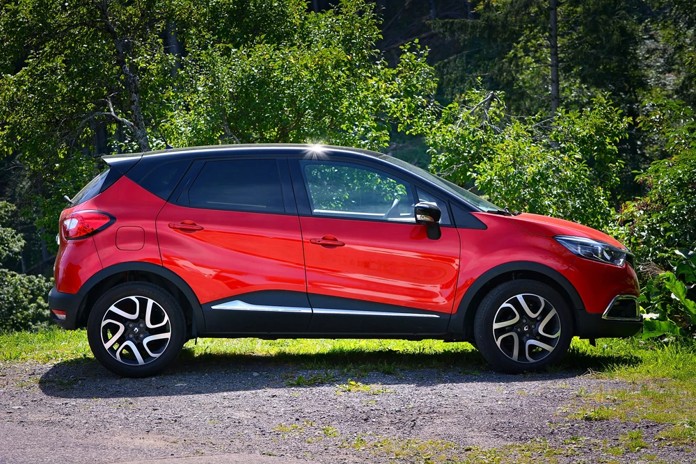 A red SUV parked in-front of some trees