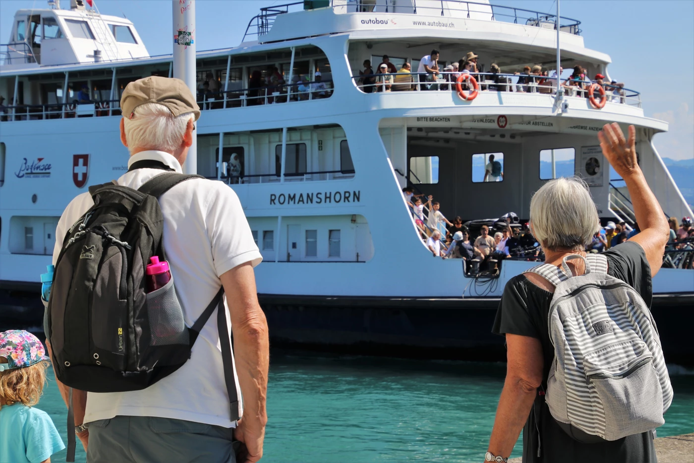 An old couple waving to a cruise ship they have just departed from