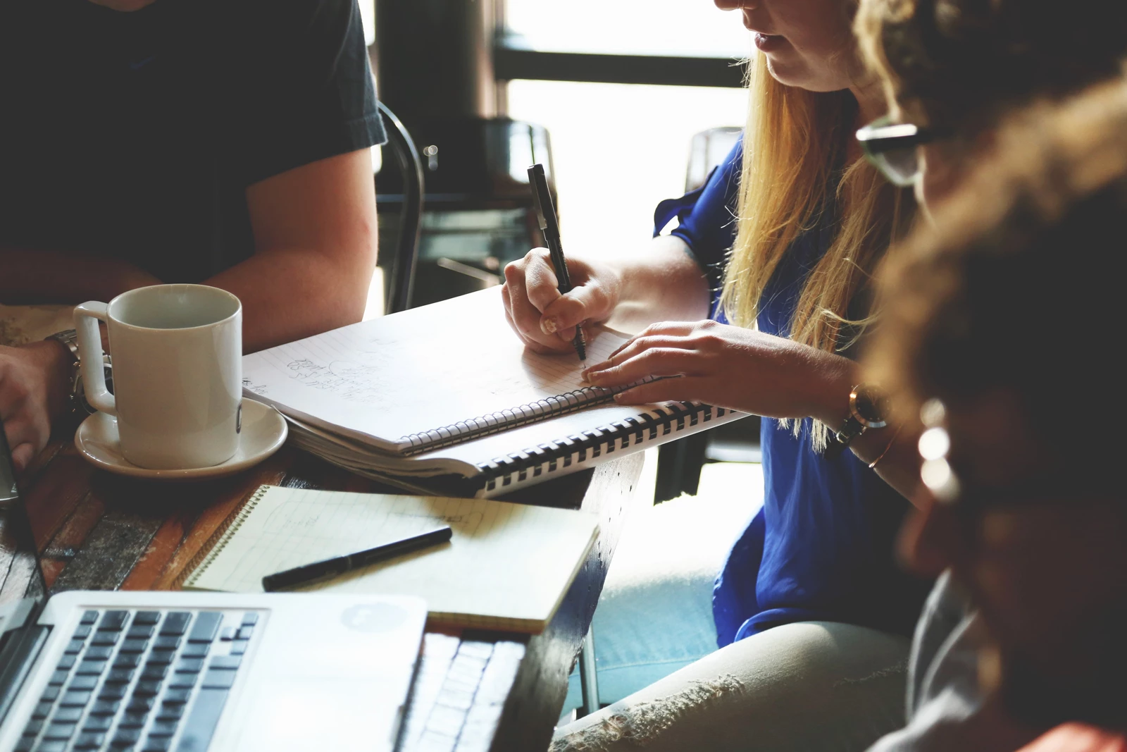 A group of office workers talking and taking notes around a table