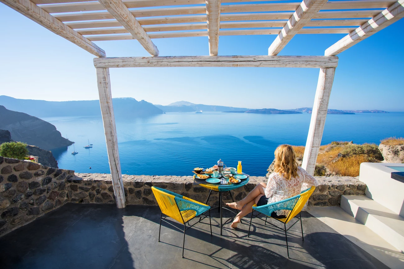 Women sitting eating breakfast on terrace balcony with a scenic view over the ocean