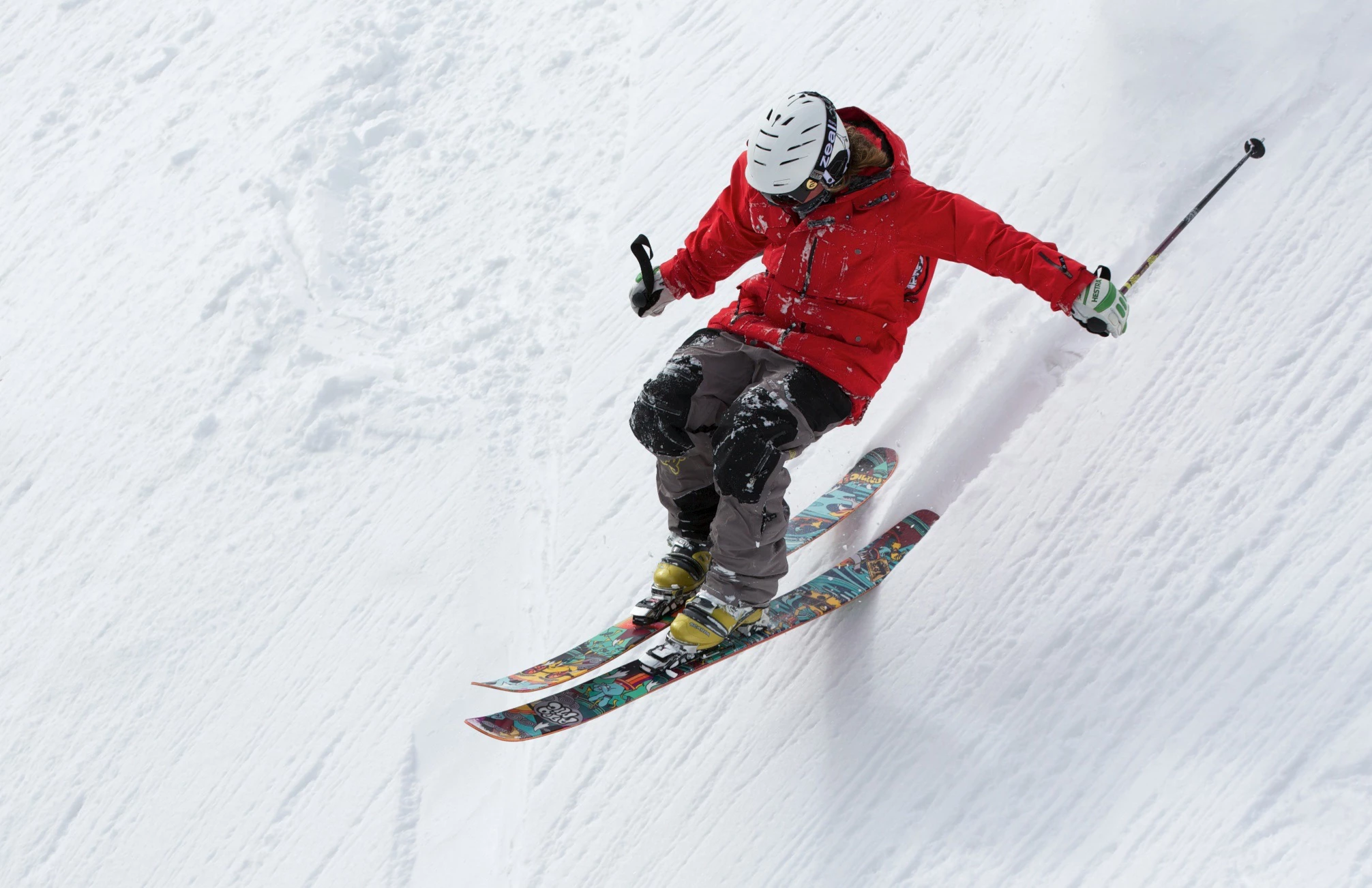 A skiier going at speed down a slope with snow launching into the air as he turns