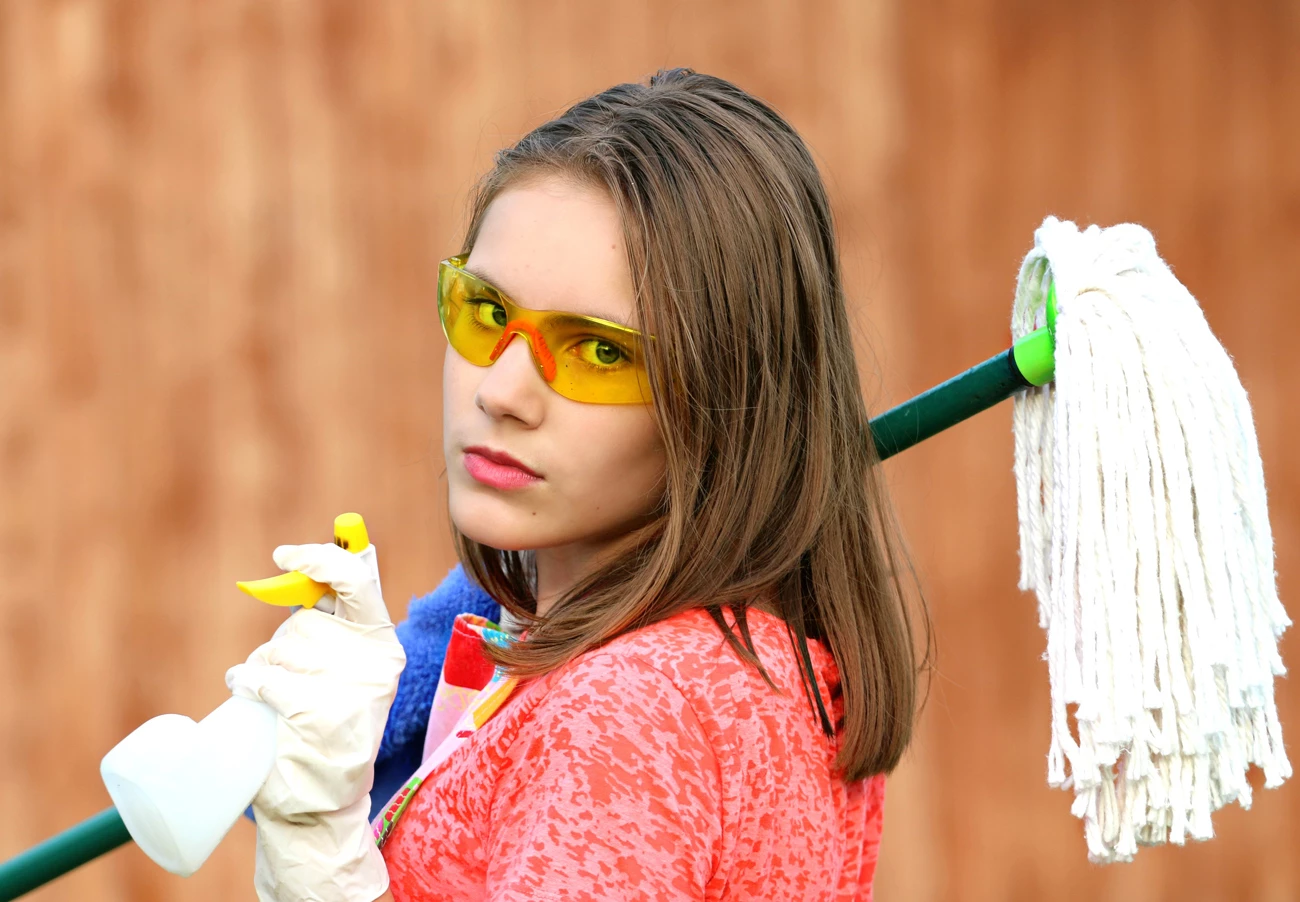A woman holding household cleaning supplies