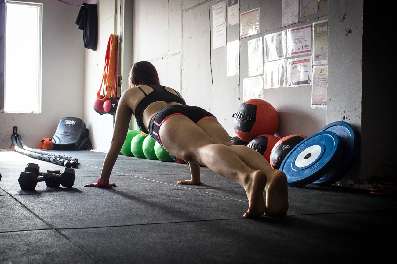 A woman planking on a mat in a gym