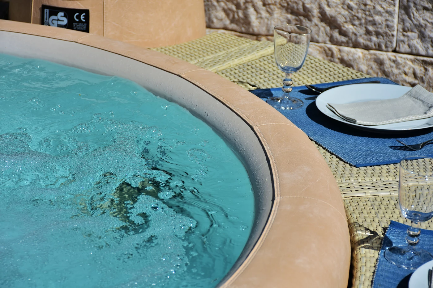 The side of a bubbling Jacuzzi with cups and cutlery set around the edge of it